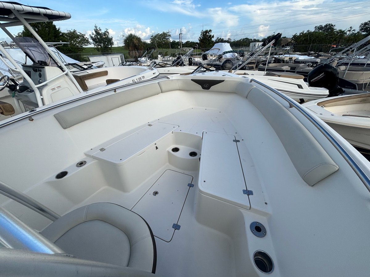 White boat cockpit with empty seating area docked at a marina with other vessels in the background
