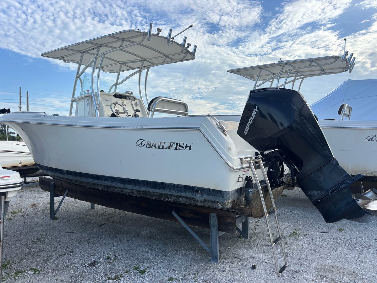 White SailFish fishing boat with T-top and outboard motor displayed in a lot with other boats