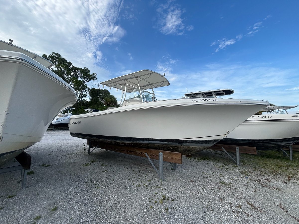 White recreational fishing boat on wooden stands in storage lot with other boats in background